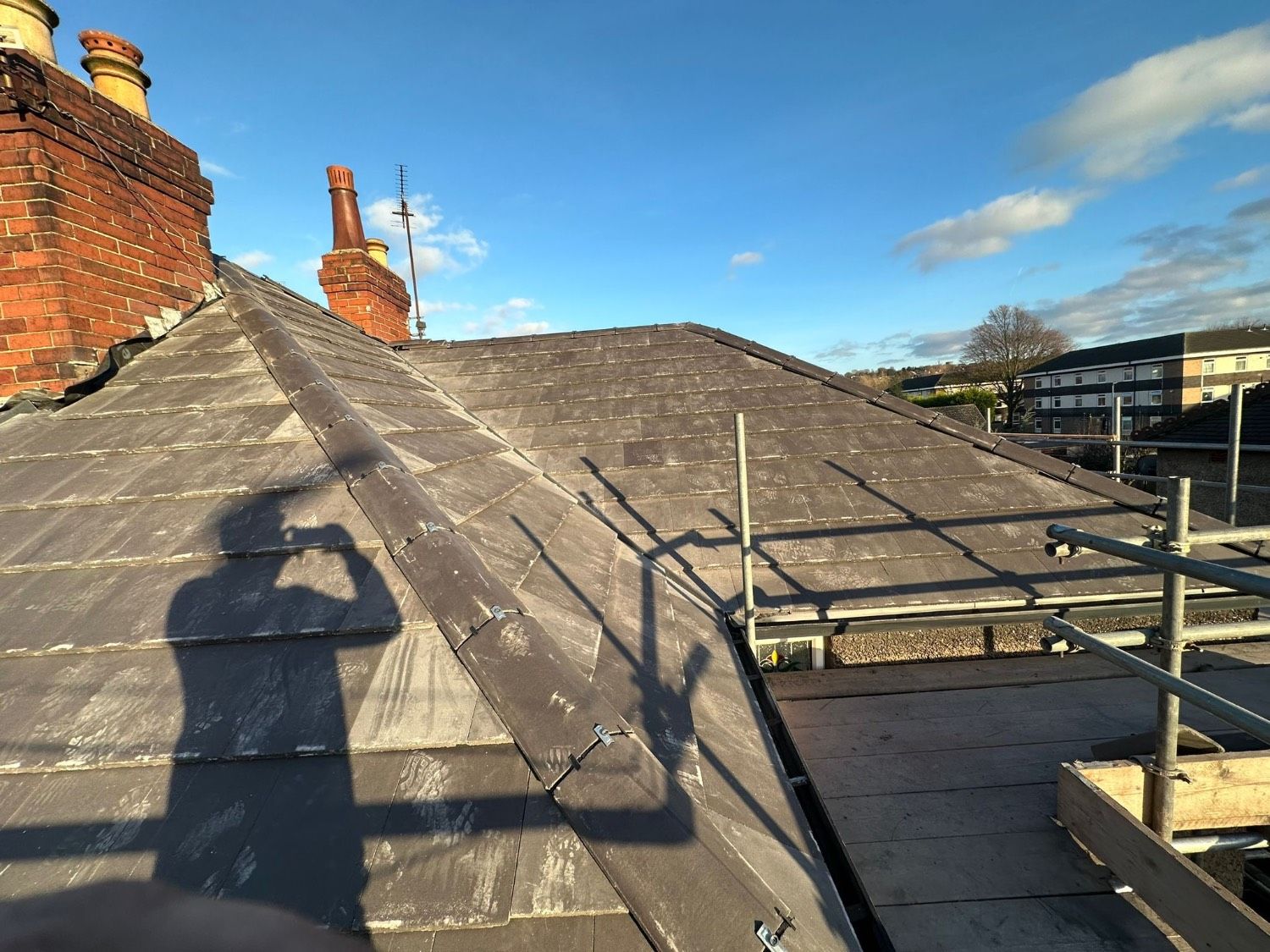 The new roof meeting the chimney stack, with clean hip and ridge lines