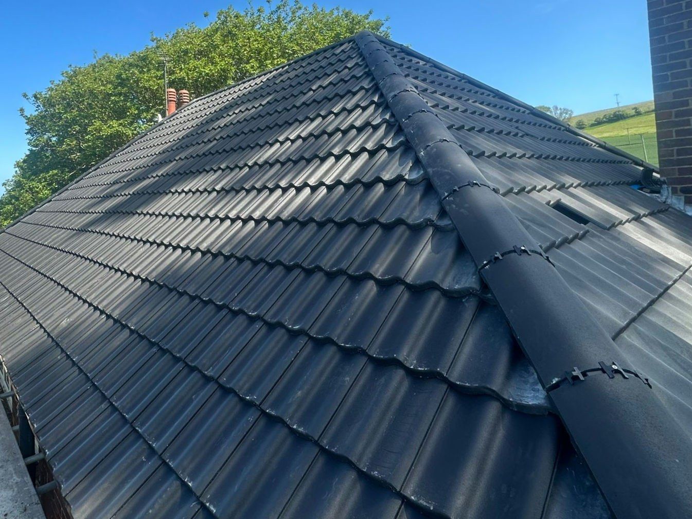 Grey tiled hipped roof with a neatly clipped ridge