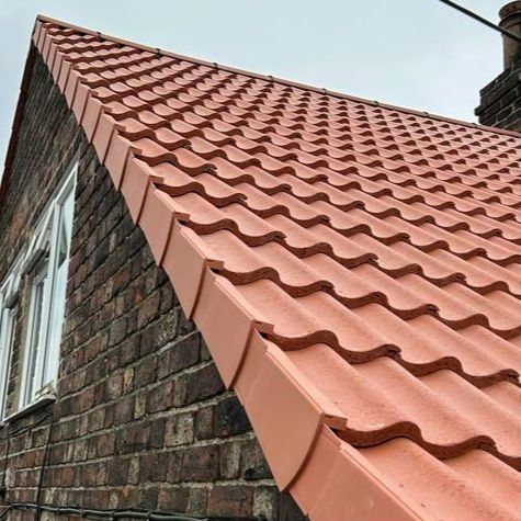New red interlocking tiles on a gable roof with a dry verge