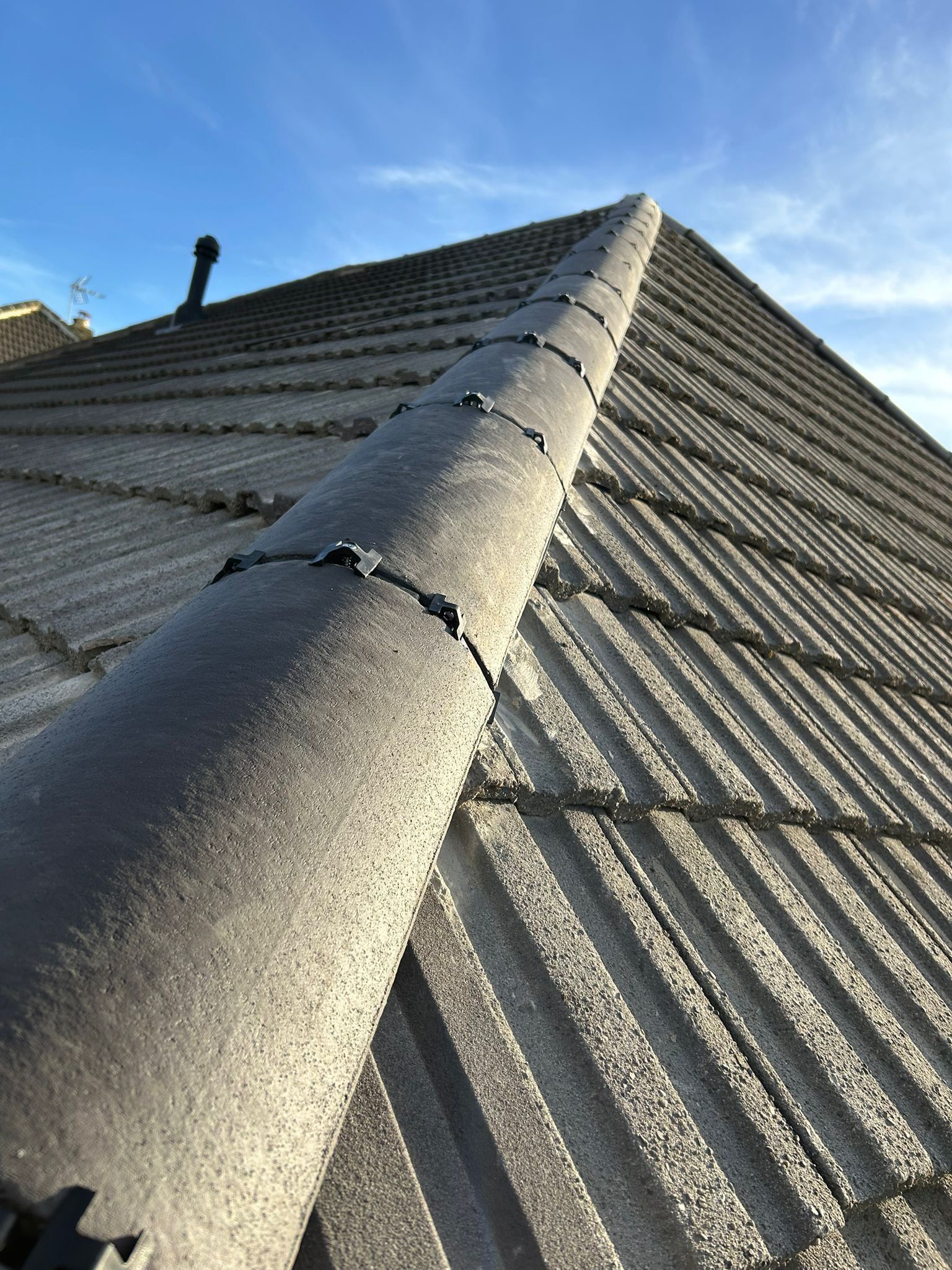 Grey dry-fixed ridge on a concrete tile roof