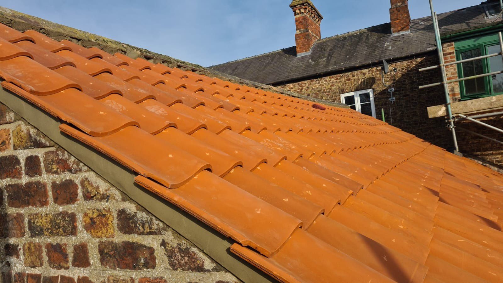 Orange clay pantiles with a dry verge on a brick gable