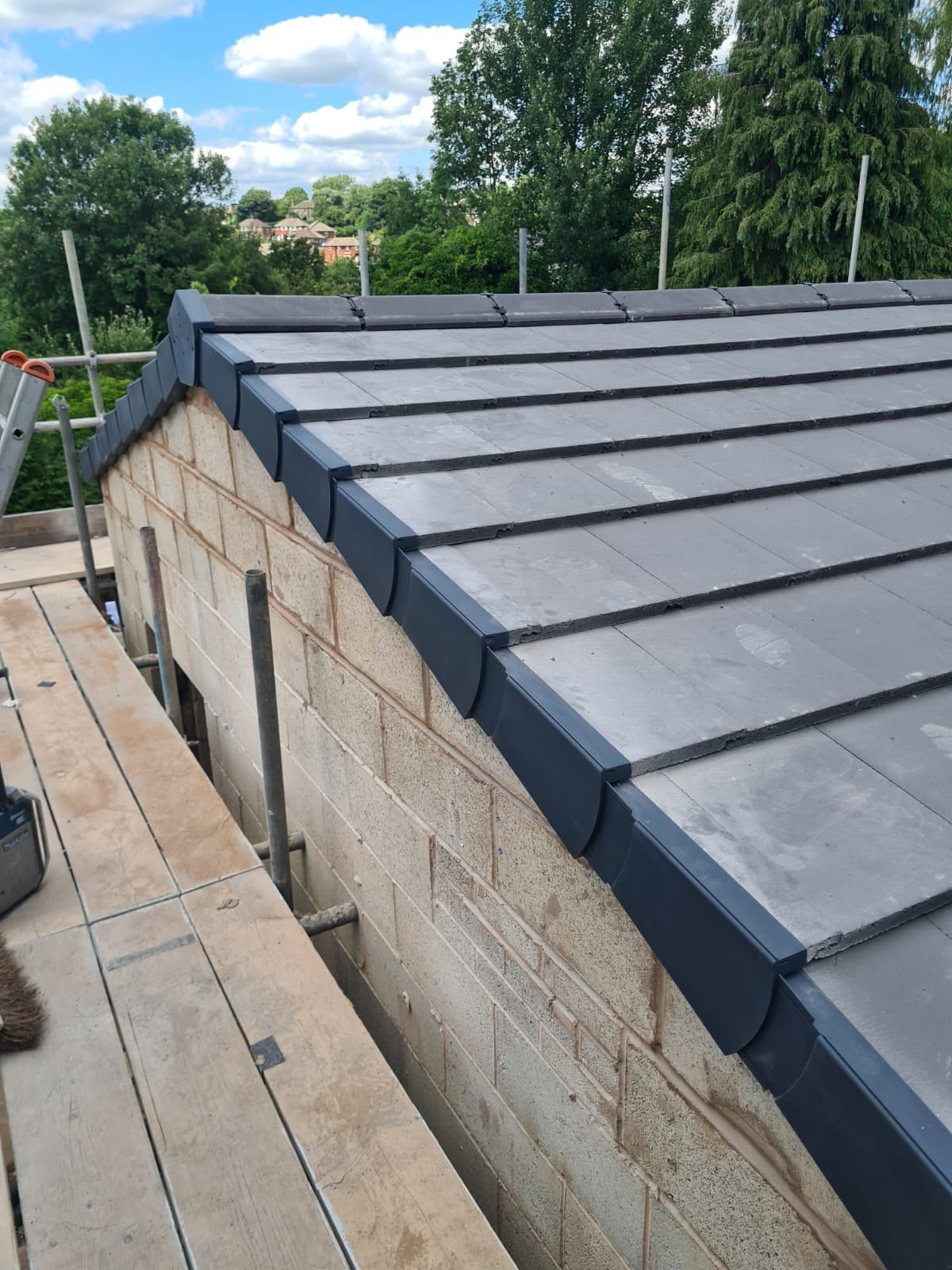 Grey dry verge on a new slate-effect gable, scaffold alongside