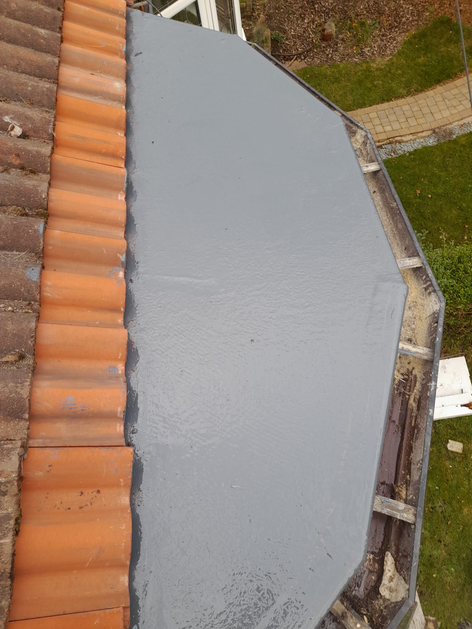 Grey GRP flat roof on a bay beside a clay pantile roof