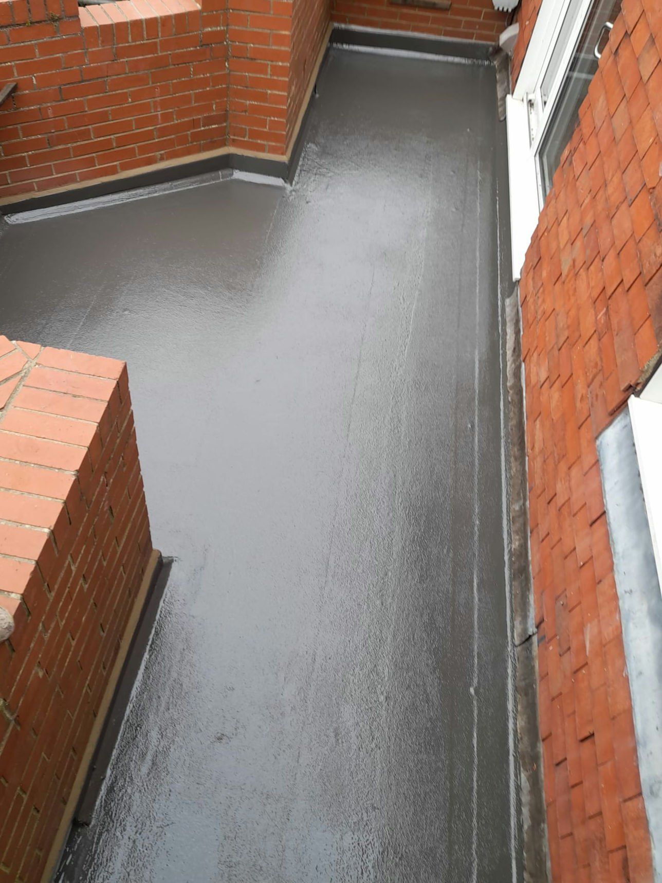 Narrow GRP flat roof between brick walls