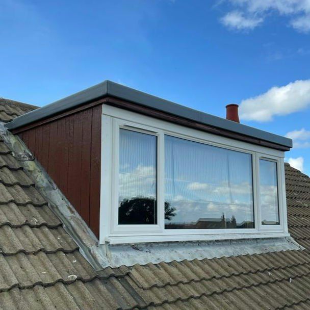 Dormer with a flat roof and wide window on a tiled roof