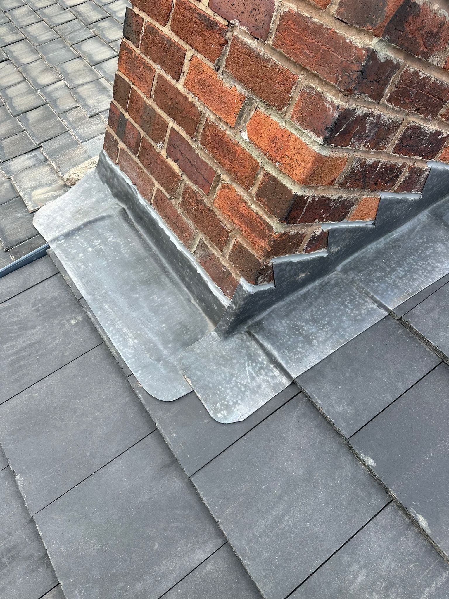 Lead step flashing around a chimney on a slate roof