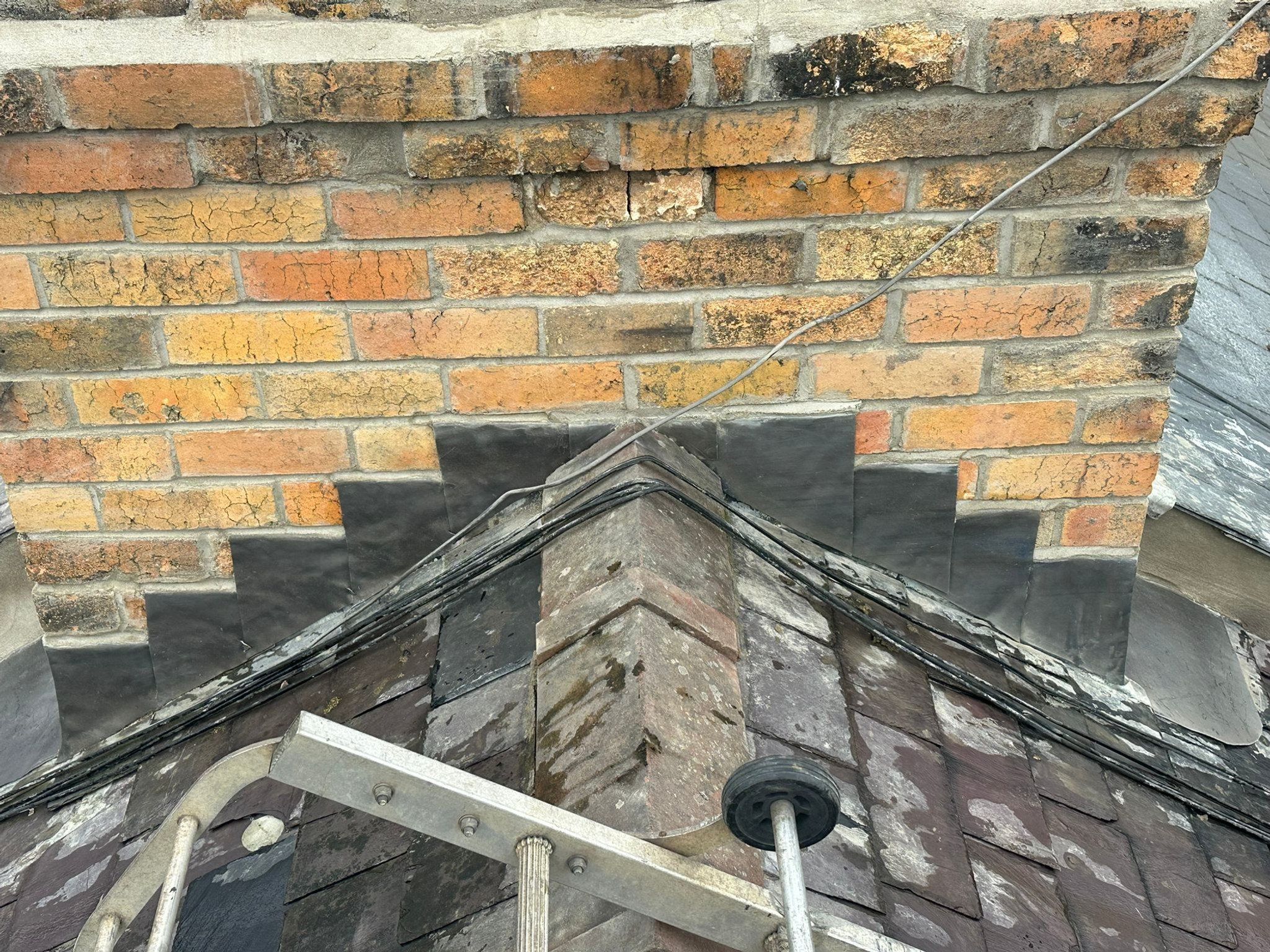 Lead flashing being fitted at the base of a brick chimney stack