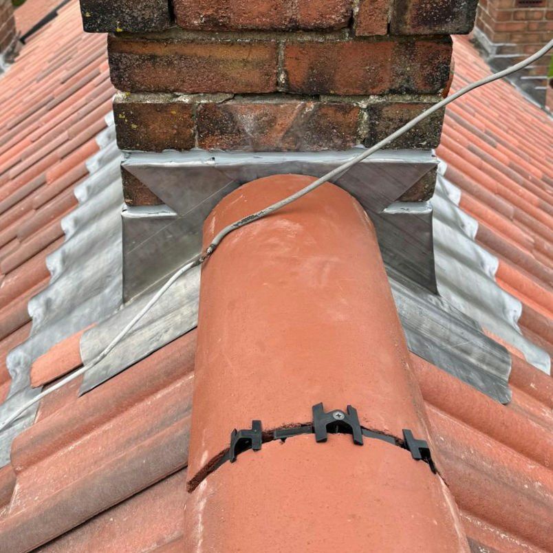 Lead saddle where a clay ridge meets a brick chimney