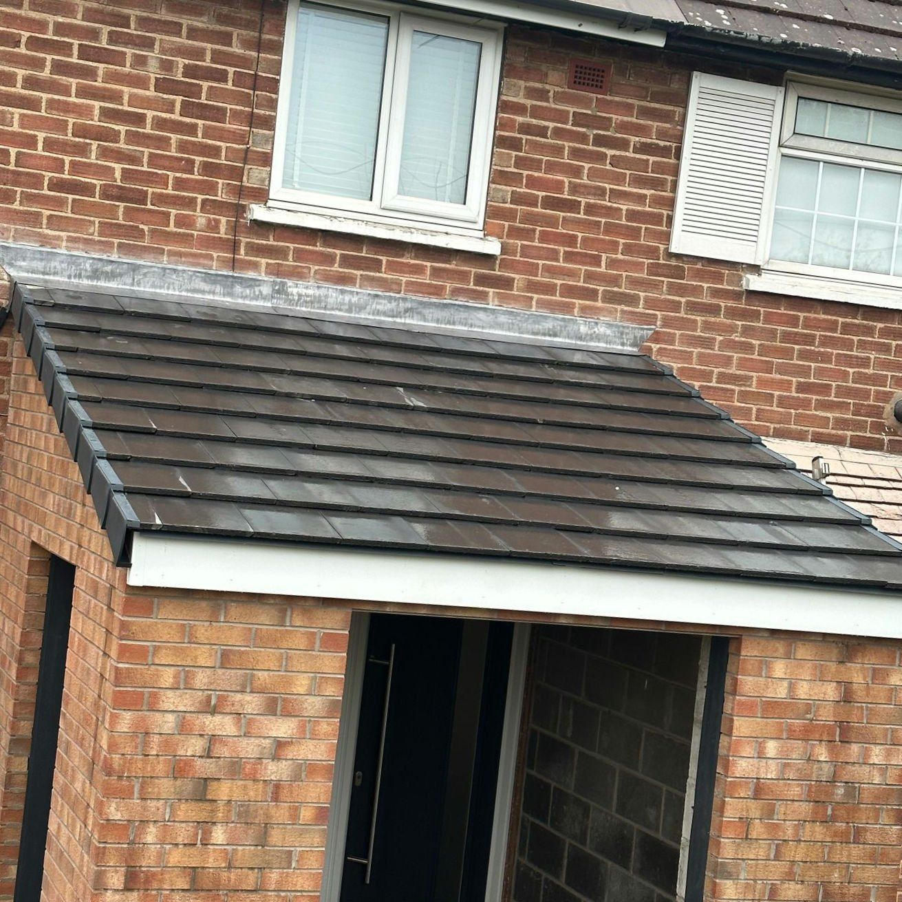 Porch roof finished in dark grey tiles with a lead flashing