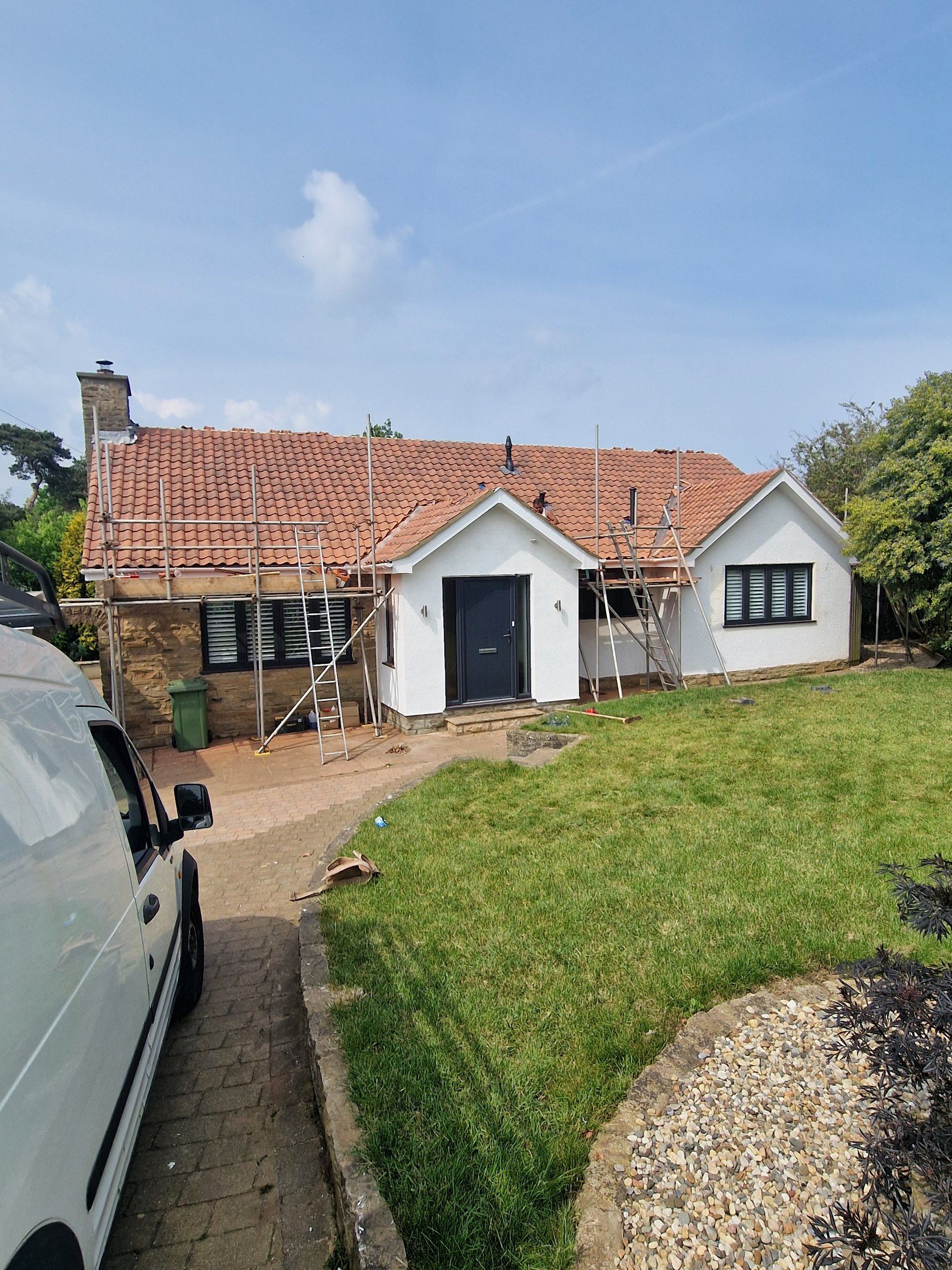 Bungalow with scaffolding around its red tiled roof
