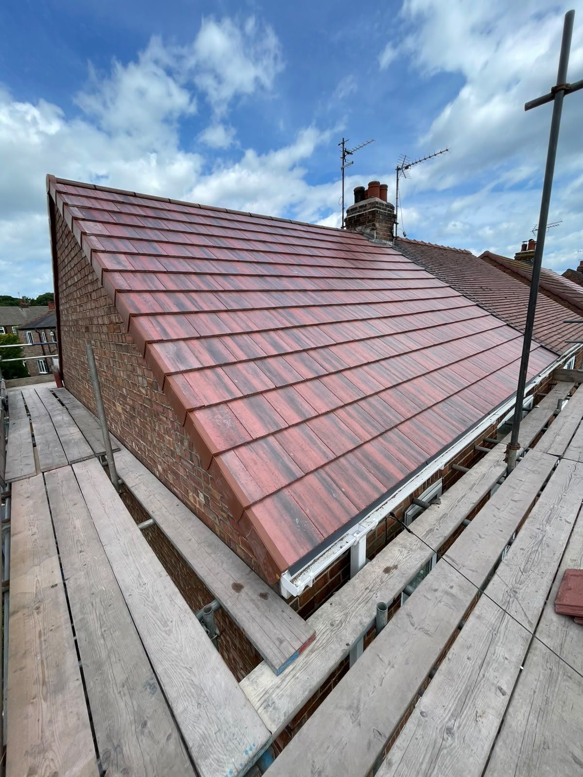 New brindle plain tiles on a gable roof, seen from the scaffold