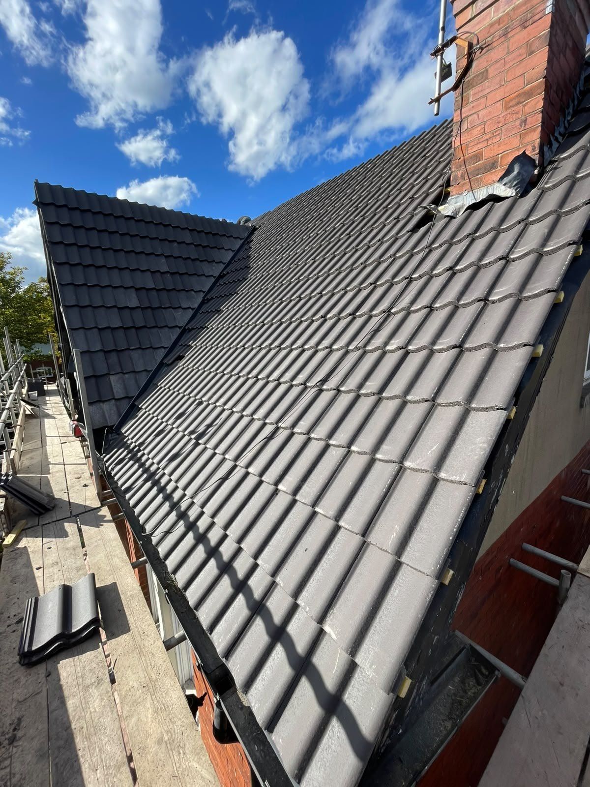 New dark grey interlocking tiles beside a brick chimney