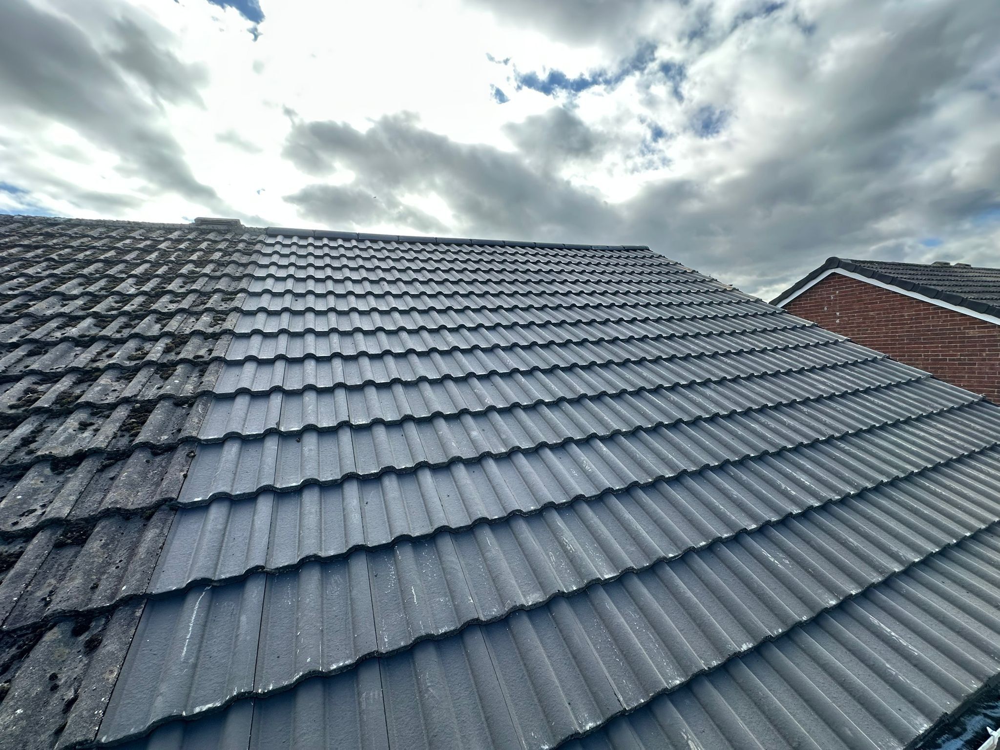New grey interlocking tiles meeting an older, weathered section of roof