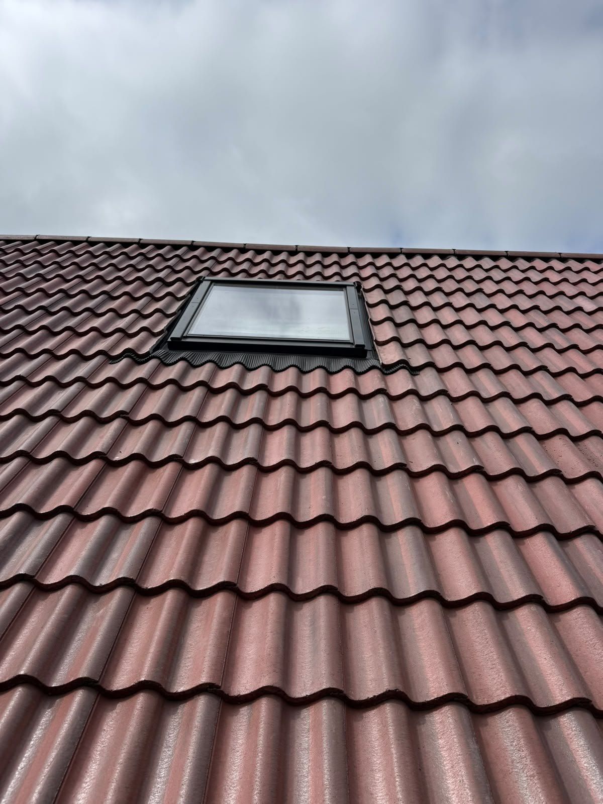 Brown interlocking tiles around a roof window
