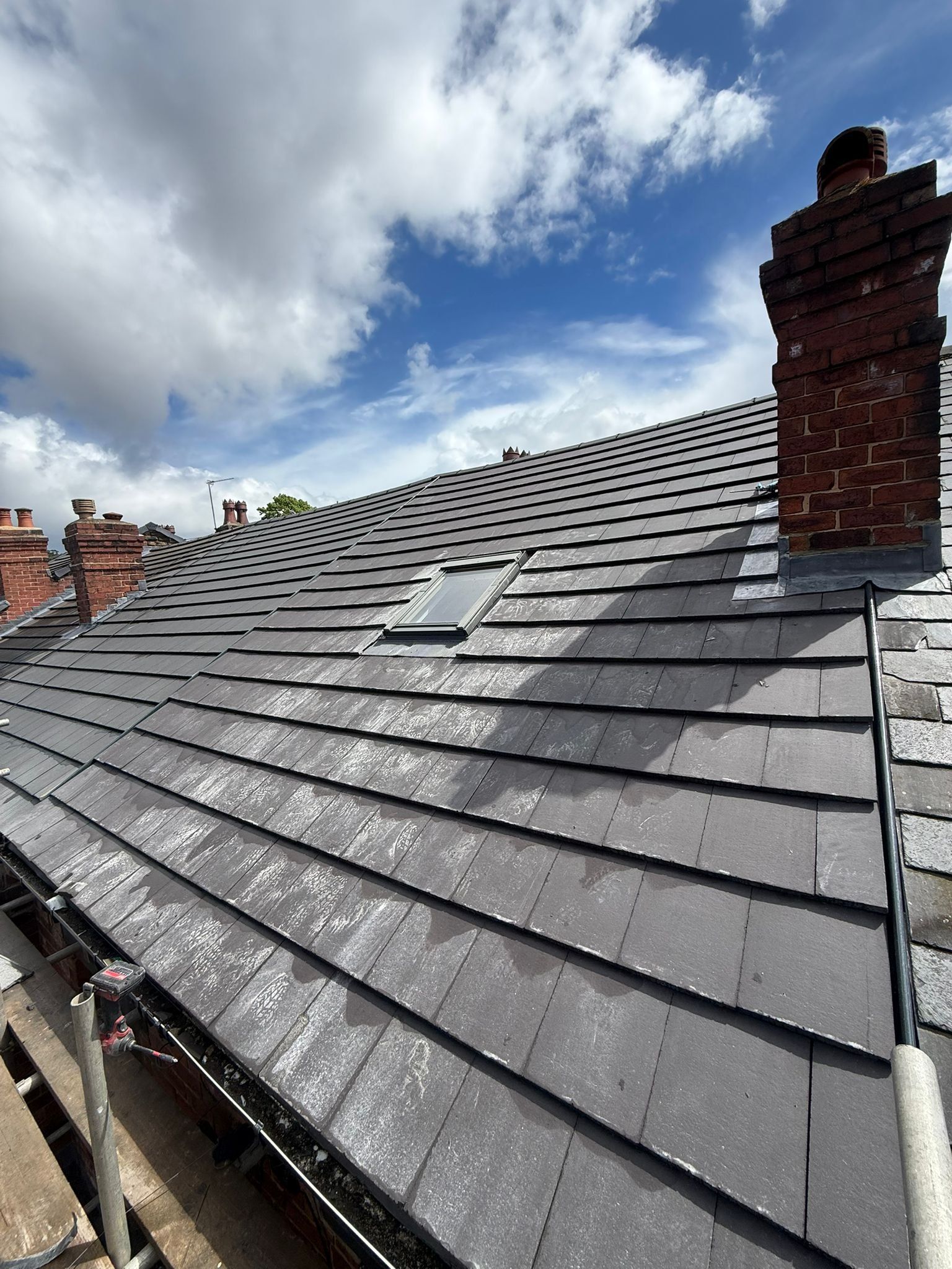 Grey slate-effect roof with a chimney and roof window