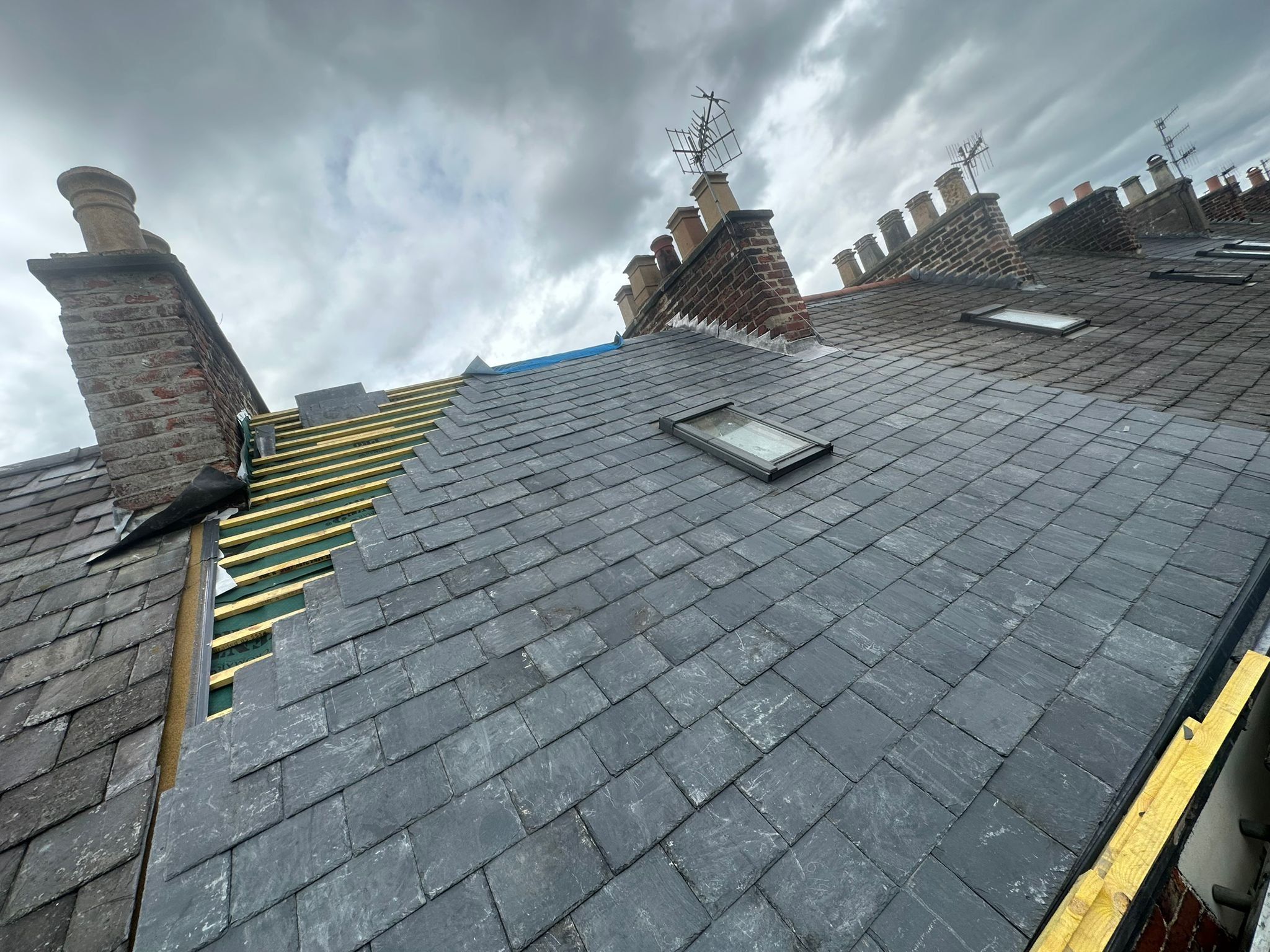 Slate roof stripped back to new battens beside the chimney stacks