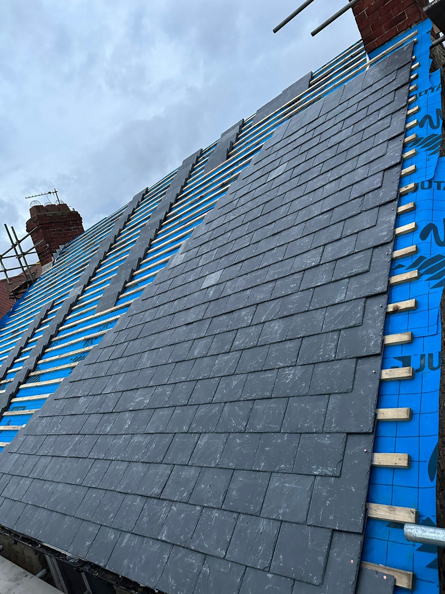 Slates being fixed over blue membrane and battens