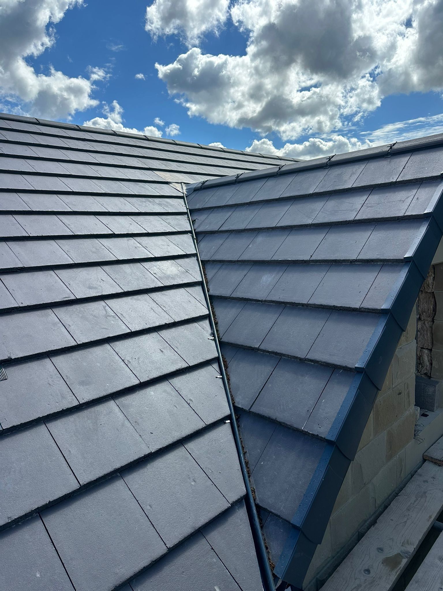 Grey slate-effect roof slopes meeting at a dormer